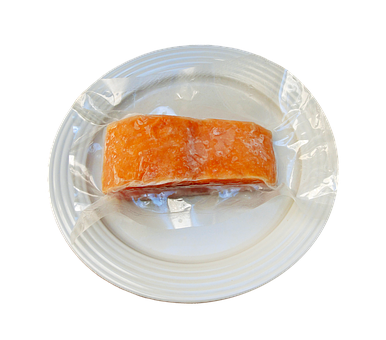 A Piece Of Food Wrapped In Plastic On A White Plate PNG
